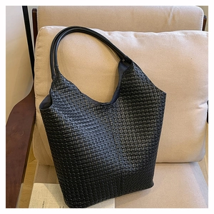 Détail du sac hobo en cuir tressé noir de haute qualité sur une chaise en tissu