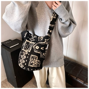 Close-up of plush paisley heart pattern and branded label on a crossbody bucket bag