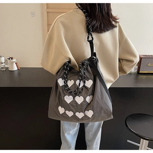 Close-up of a large grey embroidered tote bag with white heart patterns and woven straps