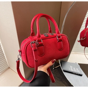 Detail of red cylinder pillow bag with pebble leather handles and silver hardware zipper