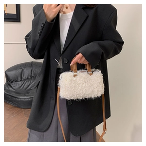 Detail of white wool-like crossbody bag with brown leather handles worn by a model