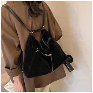 Detail of black matte leather bucket bag with gold metal buckle and slender strap