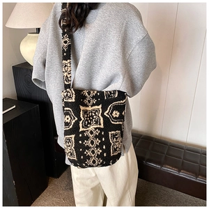 Detail view of plush crossbody bag with black and white geometric pattern on model