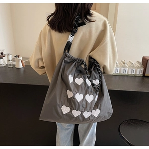 Detailed back view of a dark grey nylon tote bag with white pixel heart embroidery