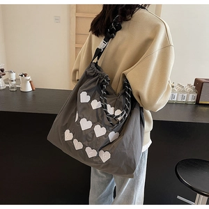 Shoulder shot of a gray drawstring tote bag with heart embroidery and braided strap