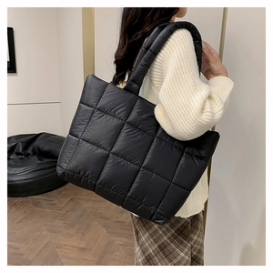 Détail du sac fourre-tout noir matelassé montrant le tissu en nylon rembourré et doux