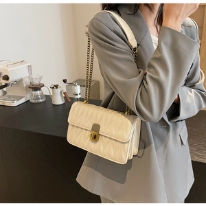 Close-up of beige quilted crossbody bag featuring V-shaped stitching and gold twist lock