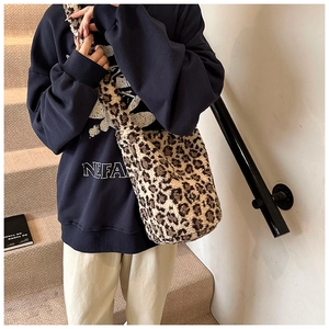 Detail of plush leopard print shoulder bag with soft faux fur texture and wide strap