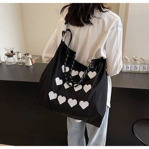 Detailed shot of large black tote bag with white heart patterns and drawstring closure