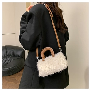 Detail of white plush crossbody bag with brown leather handles and adjustable strap
