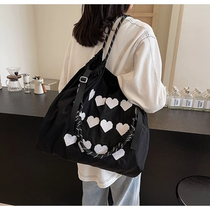 Detail of black tote bag with white heart patterns and woven shoulder strap in a cafe