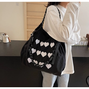 Detail of black tote bag with pixel heart patterns and adjustable woven rope strap