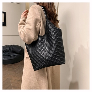 Vue détaillée du sac cabas tressé noir montrant sa texture sur l'épaule du mannequin