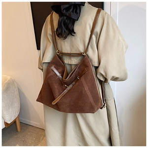 Close-up of dark brown suede tote bag with retro gold hardware and leather straps