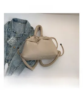 Detail view of beige padded quilted bag with soft tubular handle and drawstring closure