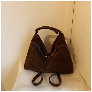 Detail of dark brown suede hobo bag featuring smooth leather handle and gold hardware