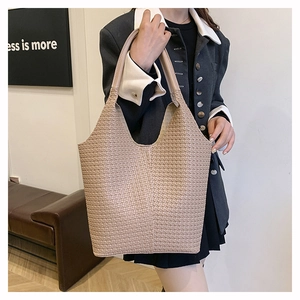 Vue détaillée de la texture tissée et de l'anse d'un grand sac cabas couleur crème