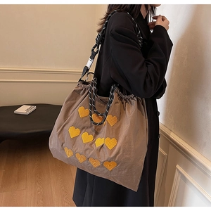 Detail of large brown tote bag with yellow heart embroidery and rope shoulder strap