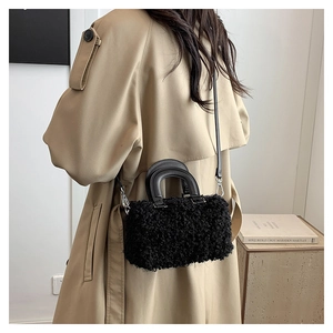 Detail of black wool-like texture bag with smooth leather handles and silver buckle