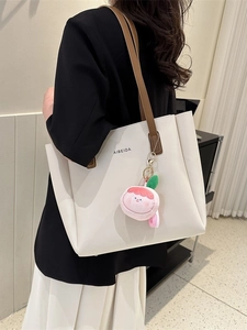 Minimalist large white tote bag with brown straps and plush charm shown on a model