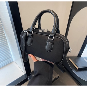 Makro-Detail der schwarzen zylindrischen Handtasche mit Leder-Mix und silbernen Metallbeschlägen