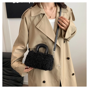 Close-up of black fuzzy lamb wool box handbag with leather strap on model outfit