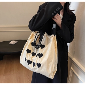 Detail view of the drawstring closure and heart embroidery on the canvas tote bag