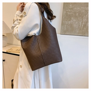 Gros plan d'un sac cabas en cuir tressé marron avec une large bandoulière
