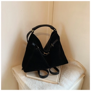 Close-up of black suede tote bag with shiny leather straps and gold metal buckles