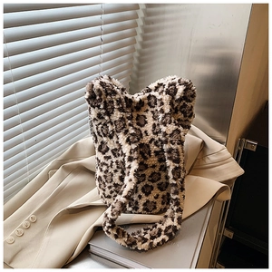 Detail of leopard print plush bucket bag with soft faux fur texture and side label