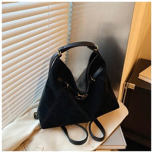Close-up of black suede tote bag with golden metal buckle under natural light shadows