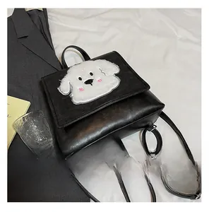 Detail showing plush cartoon dog emblem on a black square faux leather backpack flap