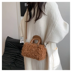 Detail of a brown faux shearling cylinder bag featuring a leather handle and metal strap