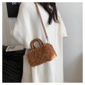Close-up of brown plush crossbody bag with leather handle and soft faux fur texture