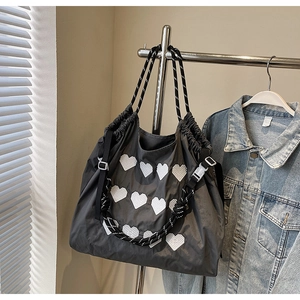 Detail of dark gray tote bag featuring white heart embroidery and woven rope shoulder strap