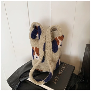 Detail of plush beige bucket bag with cute dog patterns against minimalist white backdrop