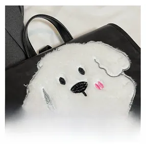 Detailed macro shot of the plush dog patch with fine embroidery on a black faux leather bag
