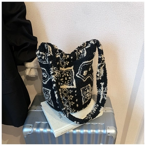 Detail of plush black and white geometric bucket bag placed on a silver suitcase