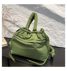 Detail of green quilted nylon handbag showing soft puffer texture and drawstring closure