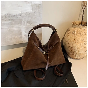 Detailed close-up of dark brown suede tote bag with leather straps and gold buckle
