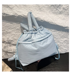Detail view of a sky blue puffy cloud tote bag with quilted nylon fabric and drawstring closure