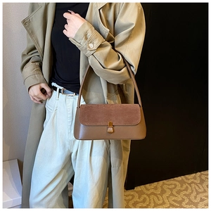 Detail of vintage brown suede shoulder bag with gold clasp shown on a trench coat model