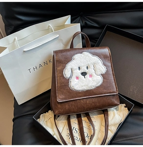 Brown vintage faux leather backpack featuring a white plush puppy patch and flap closure