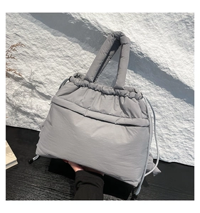 Detail of grey quilted down handbag showing soft padded texture and drawstring closure