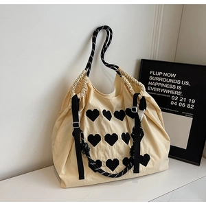 Detail of cream canvas tote bag with black heart patches and drawstring closure
