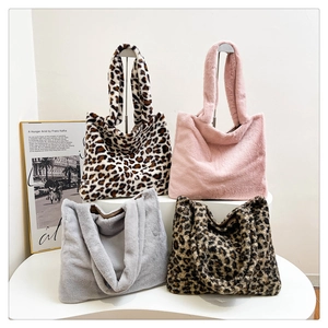 Borse tote in peluche leopardate e tinta unita su uno scaffale bianco minimalista