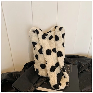 Detail of plush black and white polka dot tote bag on a stylish leather jacket