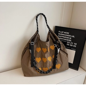 Detail of a brown tote bag with yellow heart embroidery and sturdy rope handles