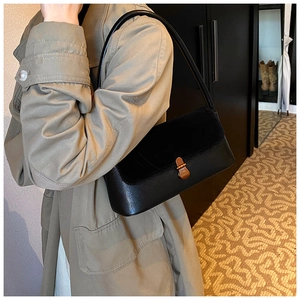 Detail of retro black underarm bag with gold clasp and sleek leather texture on model