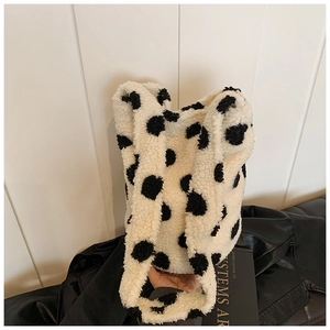 Detailed texture of plush faux fur tote bag featuring large black polka dots on beige